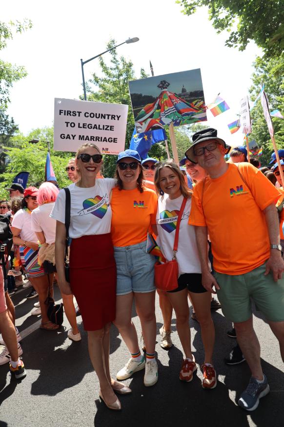 People in orange shirts hold signs.