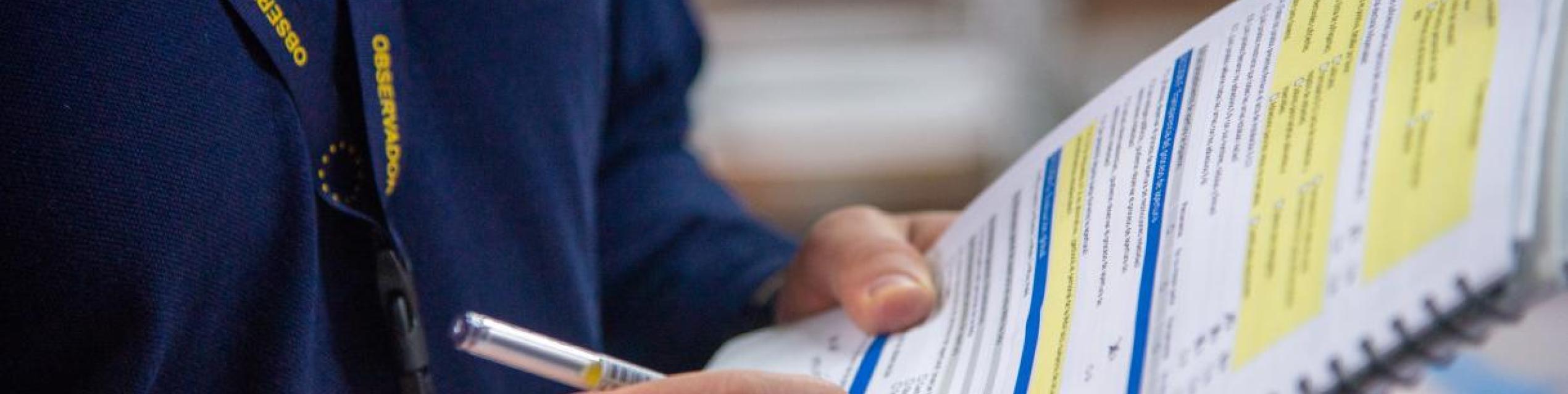 An EU Election Observation Mission observer with a clipboard