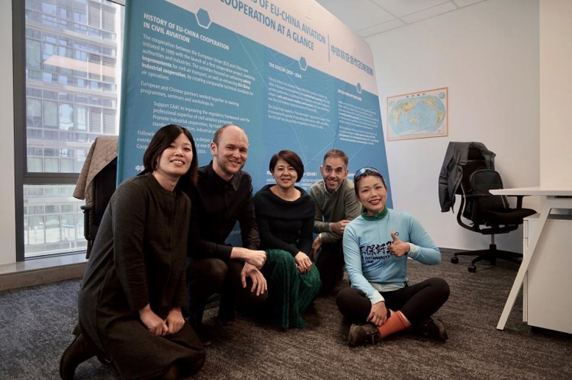 Three women and two men sitting on the floor of an office