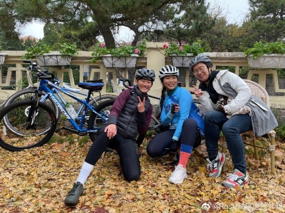 Three people posing in front of a bike