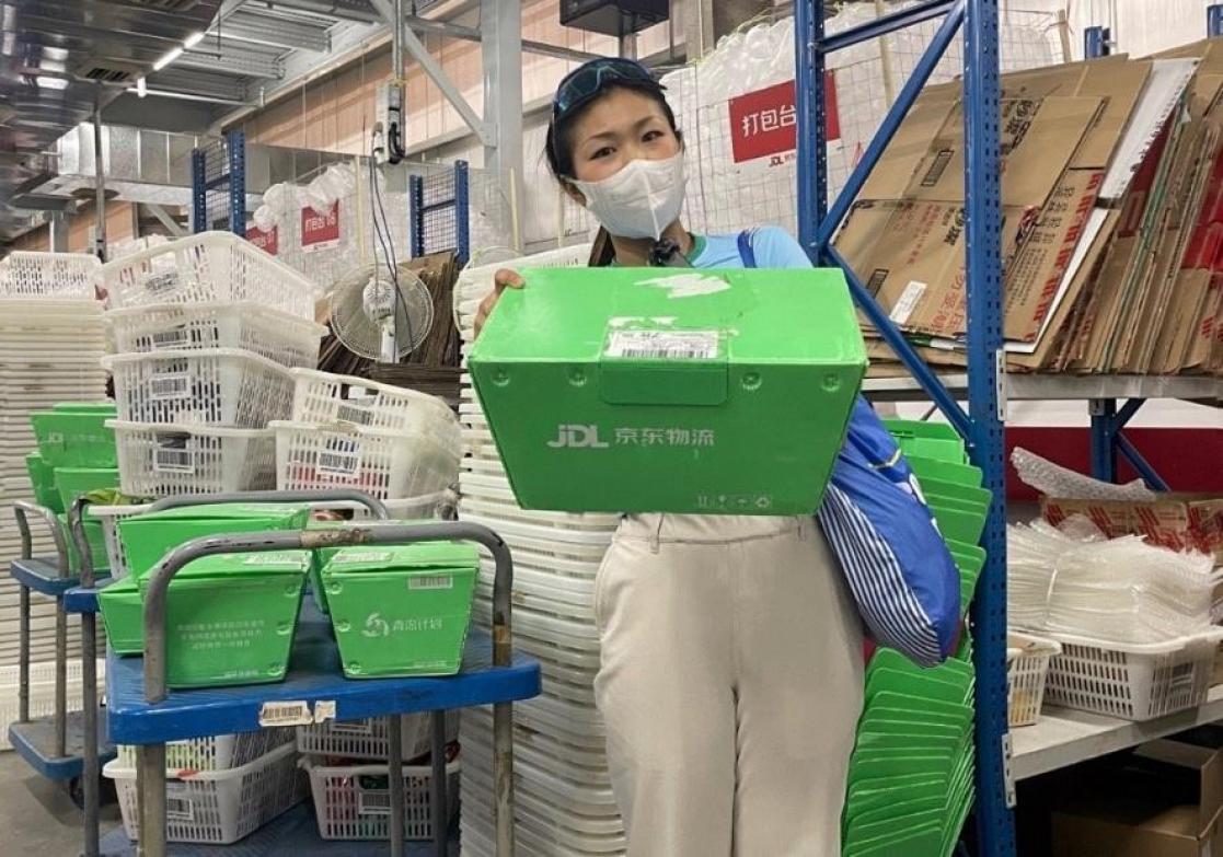 Woman with mask carrying green box