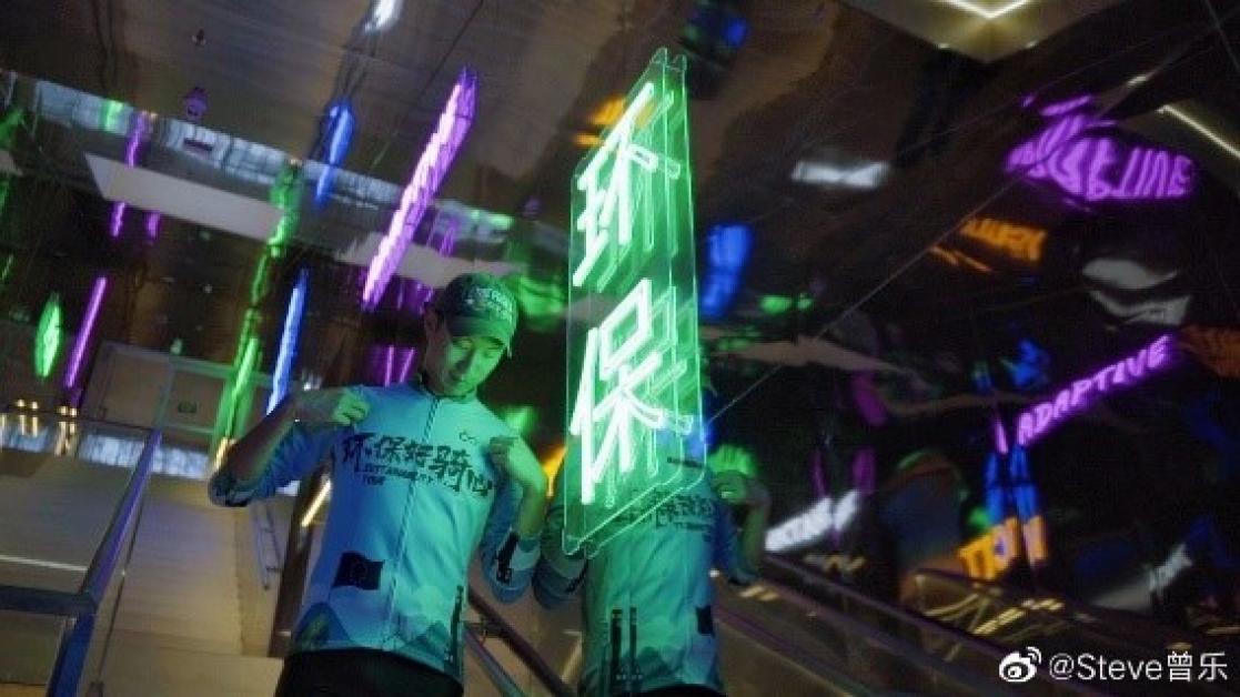 Man walking down stairs in a corridor lit by neon lights