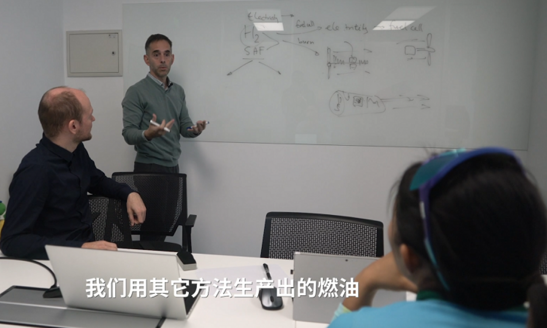 Two people listening to a man's explanation on a blackboard