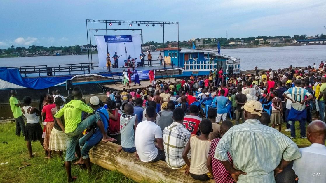 people gathered next to a river and a boat