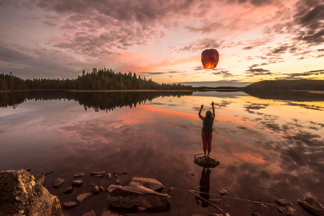 Person in a lake throwing a paper candle in the air