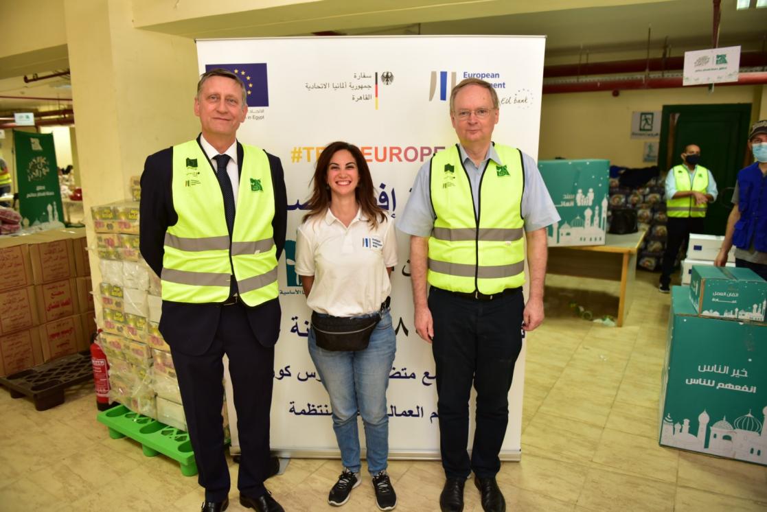 Three people smiling to the camera in front of a stand