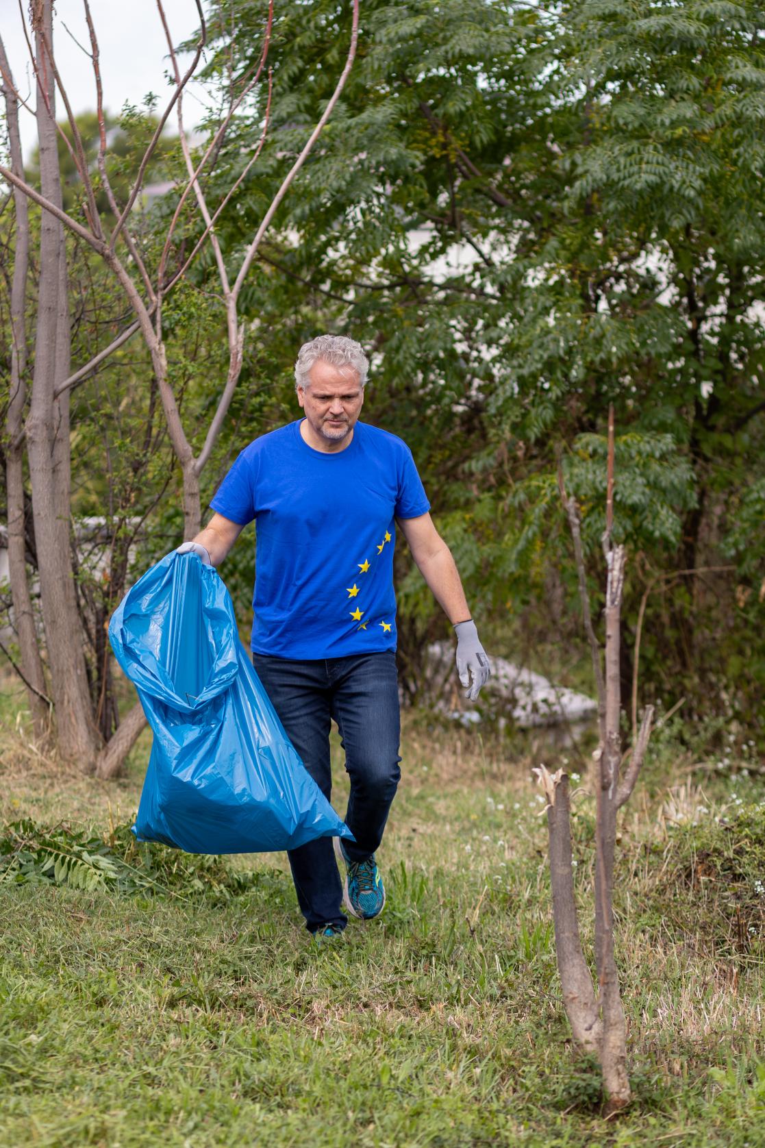 The Ambassador Sattler carrying a bag and cleaning during the EU Beach Clean up Day