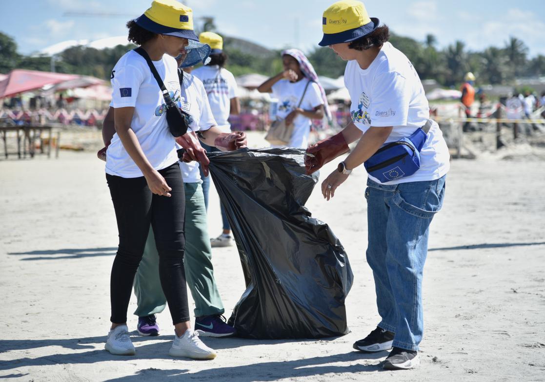 Personnes tenant un sac et nettoyant la plage