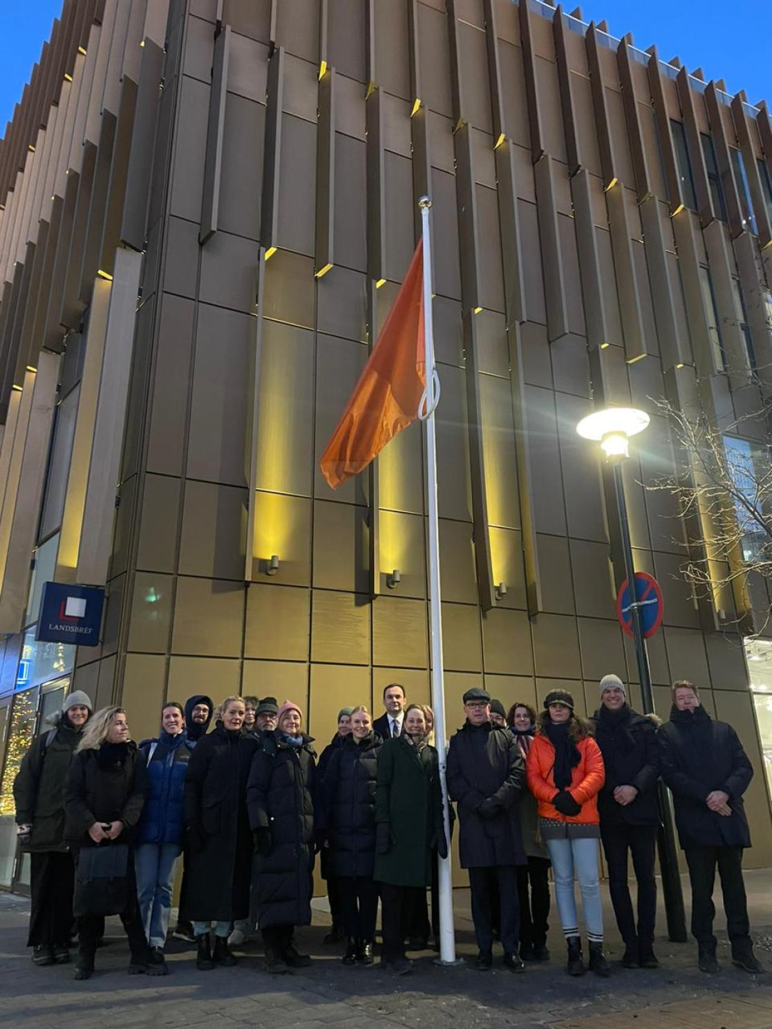 Group of Ambassadors standing next to an orange flag representing Orange the World campaign