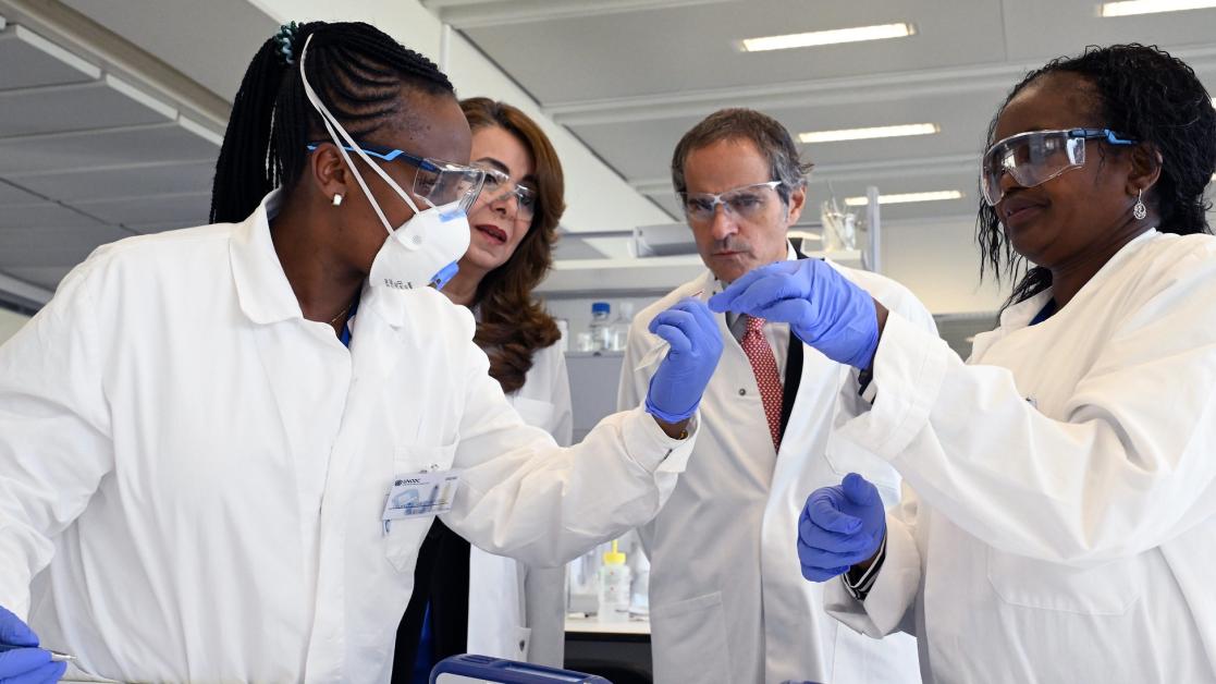 Four people in lab coats study a sample of radiocative amterial