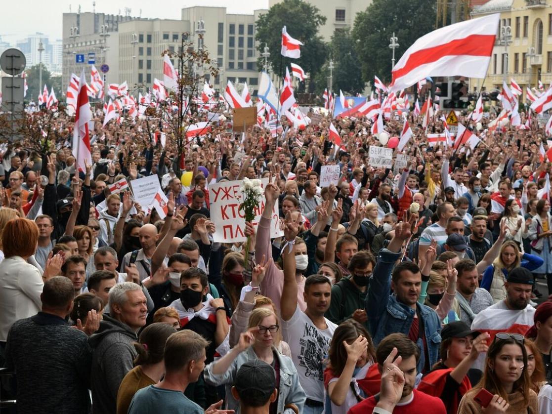 Large protest of people waving Belyorussian flags.