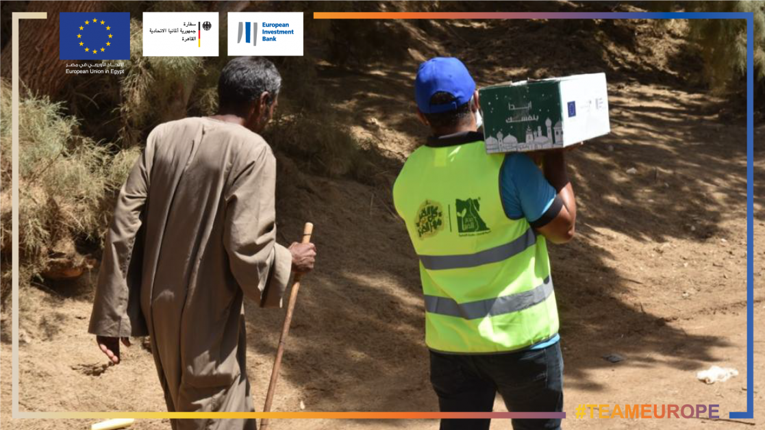 Two men walking, one of them holding a box with vaccines