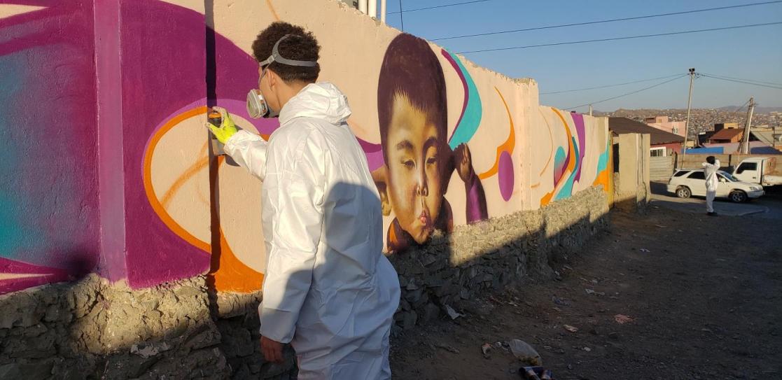 A man painting a graffiti on a wall