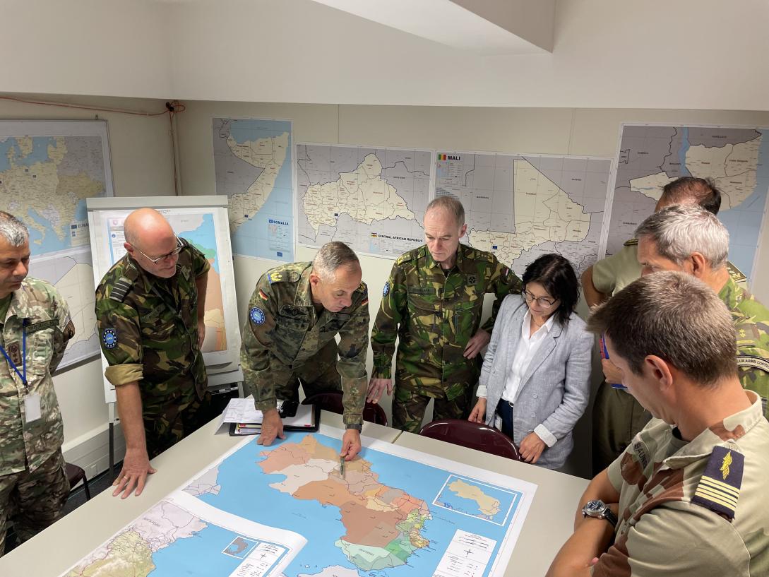 Military conference around a map with seven uniformed military and one civilian