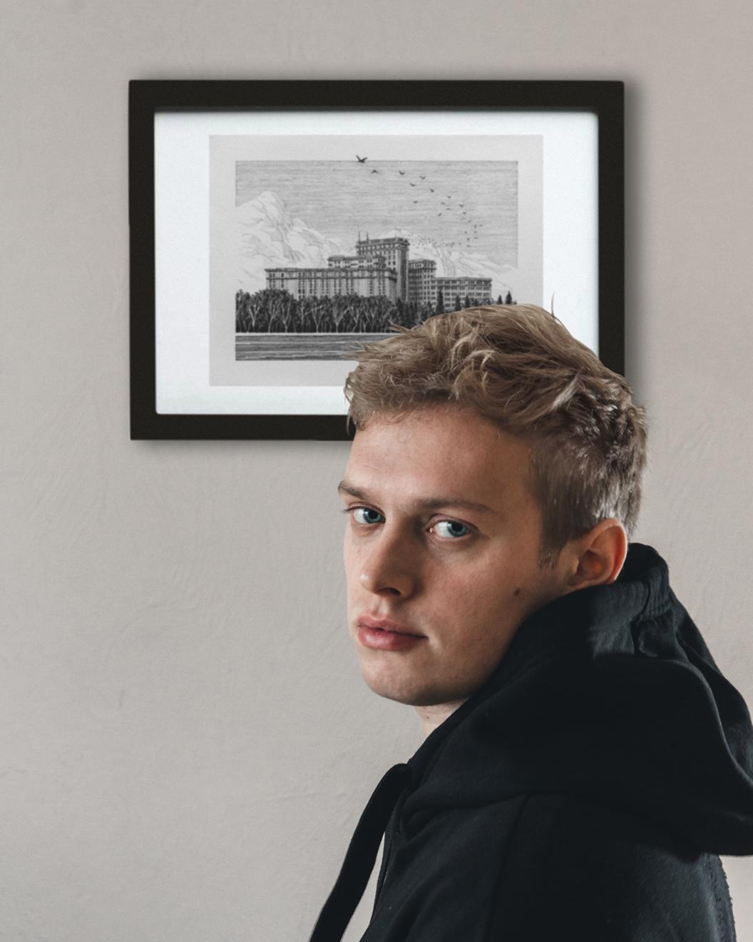 Nikita Busyak posing in front of one of his artworks