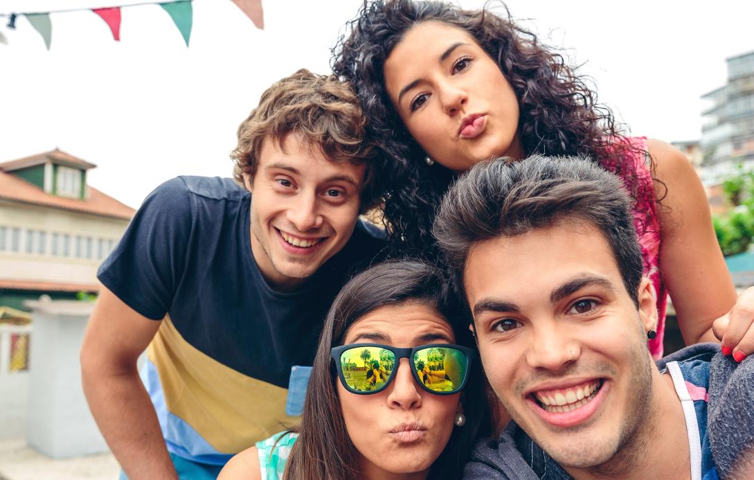 Group of 2 male and 2 female youth in smiling selfie pose.