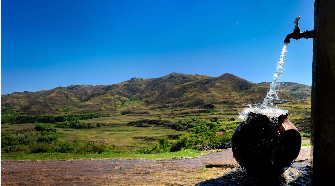 Water running from the tap with the mountains in the background