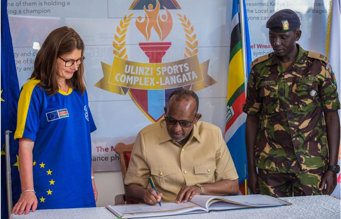 Ambassador Geiger looks on as Defence Cabinet Secretary Hon. Aden Duale signs the visitor's book.