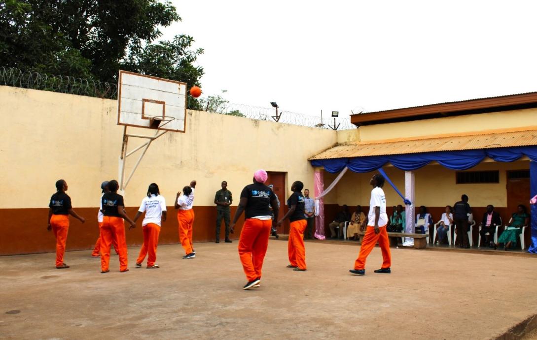 An excercise yard in a prison with prisoners playing sports.