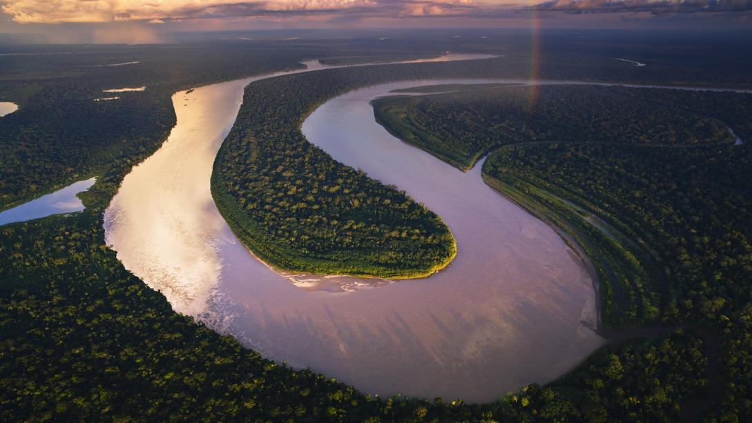 Image during a sunset of a winding river crossing the Amazon rainforest.