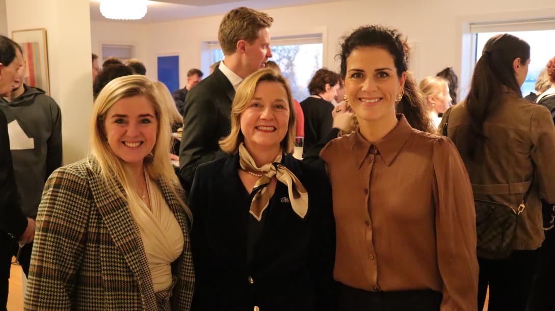 Picture of the EU Ambassador with two guests. In the background there are other guests. 