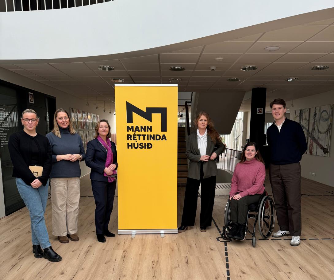 Picture of 6 people standing next to a yellow banner featuring a company logo. 