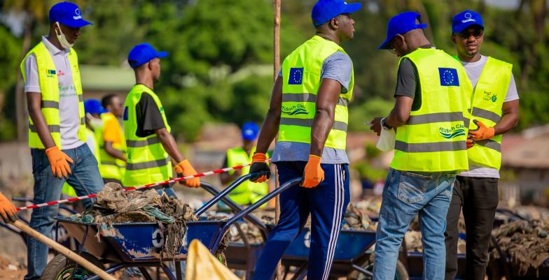 Des volontaires poussant des brouettes remplies de déchets