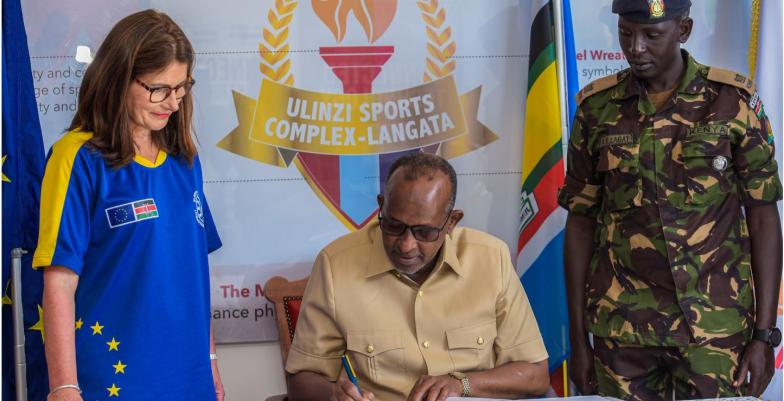 Ambassador Geiger looks on as Defence Cabinet Secretary Hon. Aden Duale signs the visitor's book.