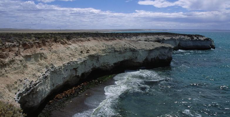 A coastal landscape with the sea breaking on the rocks.