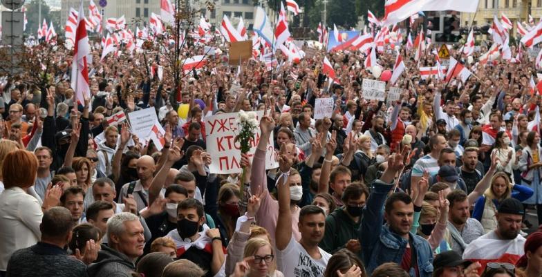 Large protest of people waving Belyorussian flags.